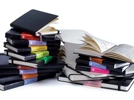 Pilhas de cadernos Moleskine coloridos, alguns abertos e outros fechados
