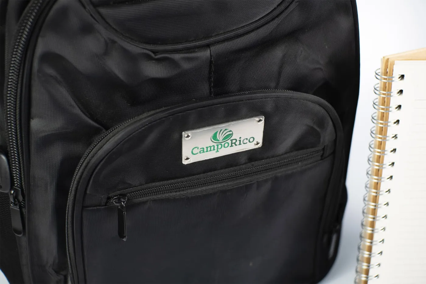 Detalhe da placa metálica gravada com o logotipo aplicada no bolso da mochila corporativa