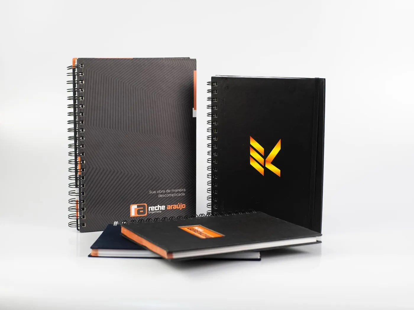 Cadernos com nome da empresa na capa dura, padronagem em relevo e logotipo metalizado