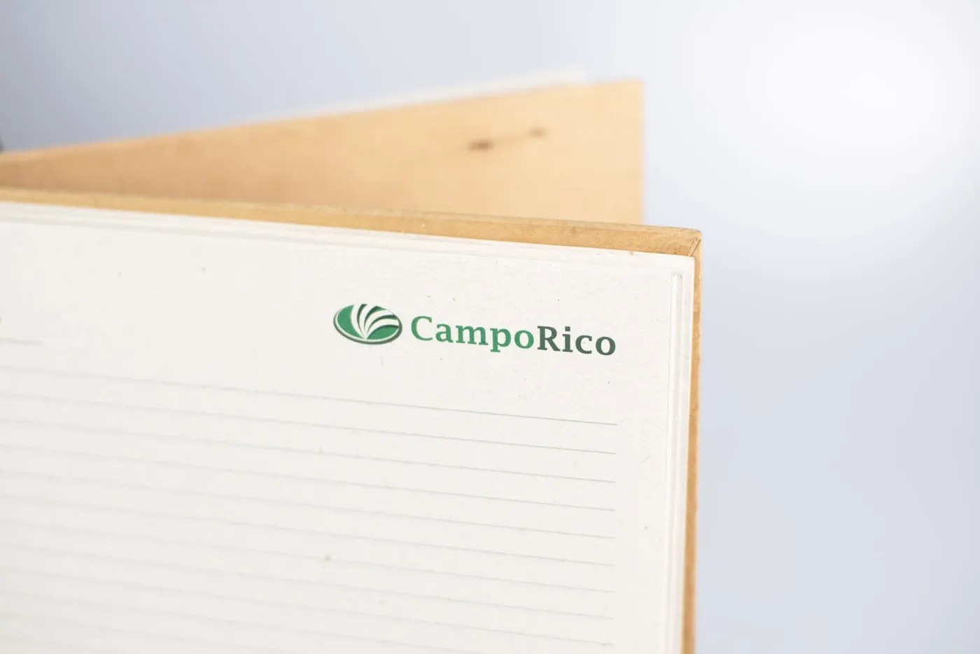 Detalhe do miolo em papel reciclado com logotipo impresso em verde e capa dura kraft