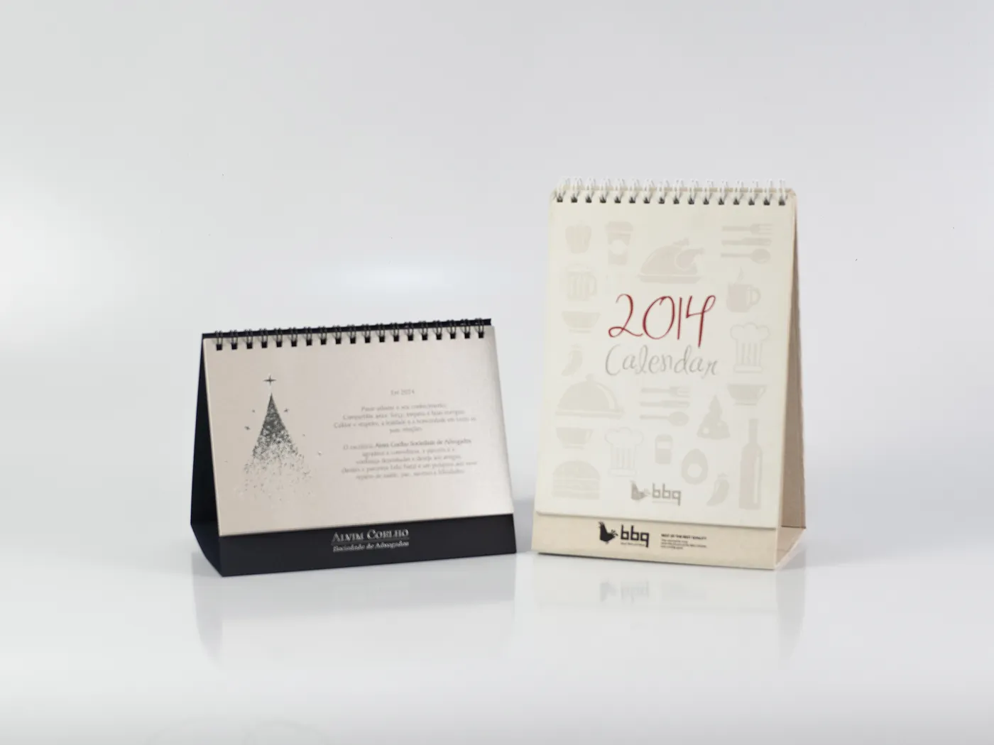 Dois calendários de mesa em papéis e formatos diferentes, com base triangular