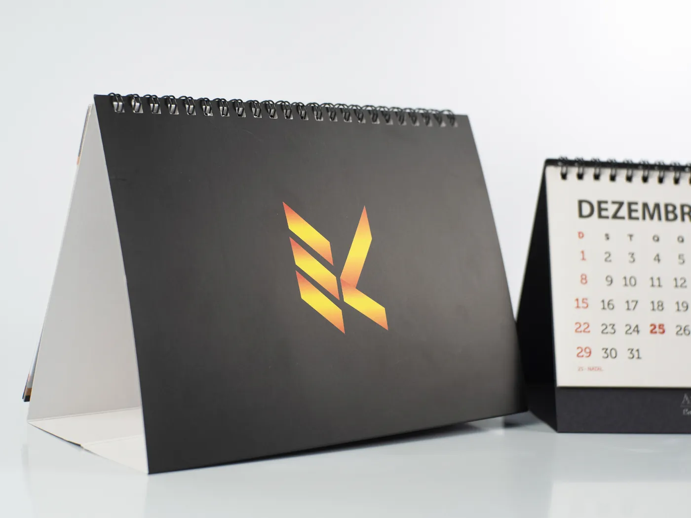 Calendário de mesa com capa preta e logotipo impresso em degradê laranja
