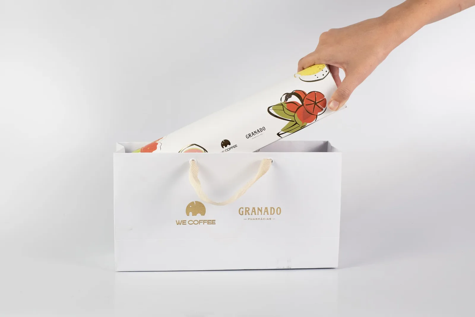 Sacola premium recebendo caixa tubular ilustrada, compondo kit de presente