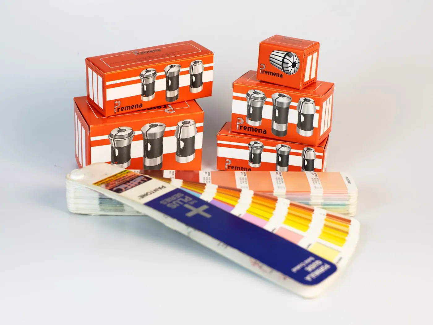 Conjunto de caixas Premena empilhadas ao lado do guia Pantone Plus Series